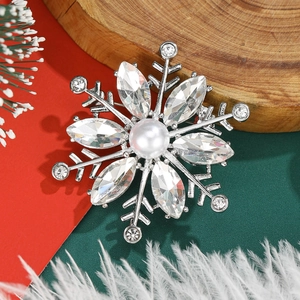 Macro shot of silver snowflake brooch with crystals and pearl on Christmas background