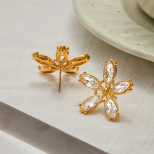 Détail de boucles d'oreilles fleurs dorées avec cristaux de zircone de taille marquise