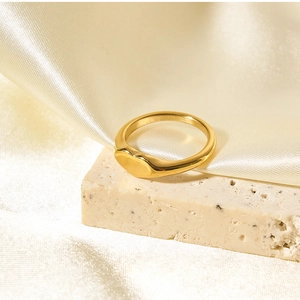 Macro view of a gold-plated heart signet ring on travertine stone with silk backdrop