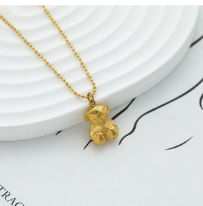 Macro detail of 18K gold 3D geometric bear pendant on elegant ball chain necklace
