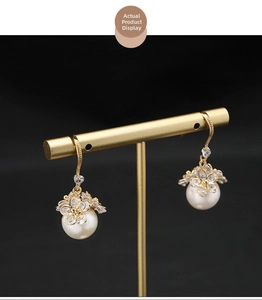 Detail of gold floral earrings with zircon heart, flower petals and white pearls