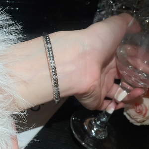 Detailed macro view of an 18k silver plated bangle with zircons worn on a wrist