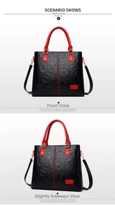 Detail of black embossed leather handbag with red trim and golden metal hardware