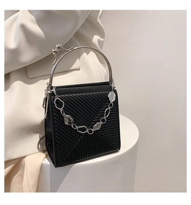 Detail of black leather handbag featuring V-shape quilting and bright silver metal handle