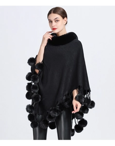 Detailed view of the black knitted poncho with faux rabbit fur collar and pompoms