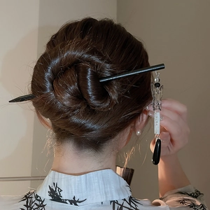 Macro view of Chinese butterfly hair pin with black water drop tassel on elegant bun