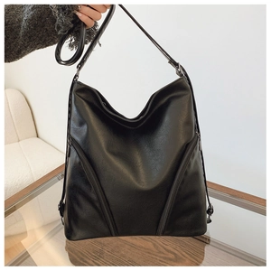Detailed view of black PU leather shoulder bag with side zipper decor on glass table