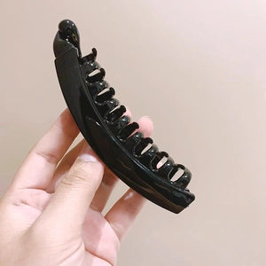 Dettaglio di un grande fermaglio a banana nero con denti ricurvi e trama in resina