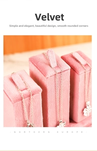 Close-up of pink velvet jewelry necklace stands with slots on warm wood background