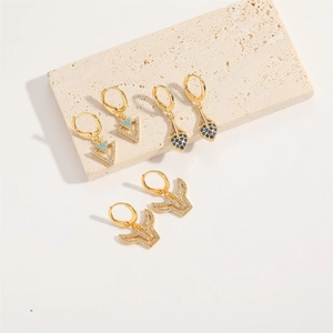 Three pairs of golden Evil Eye earrings with blue and white zircons on a stone plate