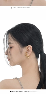 Close-up of a minimalist irregular gold liquid-line ear cuff on a model's ear