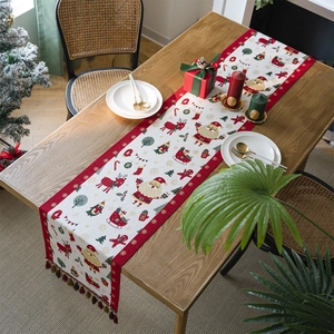 Festive Christmas table runner with red tassels and holiday pattern on wooden table