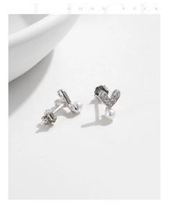 Detail of silver heart earrings with sparkling crystals and white hanging pearls