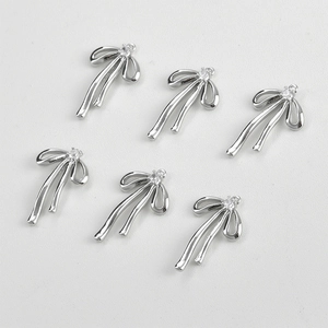 Detailed view of silver bow-shaped pendants with clear zircon for jewelry making