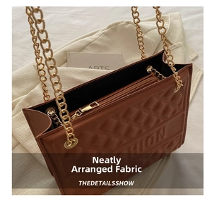 Detail of golden metal zipper and chain strap on brown embossed tote bag