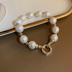 Detail of elegant pearl bracelet with gold plating and crystal-encrusted round clasp