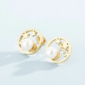 Vue macro de boucles d'oreilles étoiles dorées avec perle centrale et détails en strass