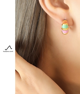 Close-up of model wearing C-shaped stainless steel earrings with colorful enamel stripes