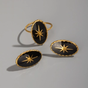 Detail view of gold and black oval jewelry set including star pattern ring and earrings