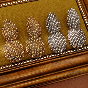 Dettaglio di orecchini vintage a goccia con cristalli in oro e metallo scuro