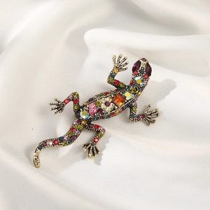 Lizard brooch with colorful rhinestones on vintage gold base, set on white silk fabric