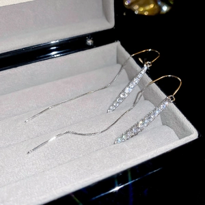 Macro detail of silver drop earrings with pavé zircons and elegant long chain tassels