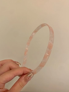 Close-up of slim pink marble textured acrylic headband with a smooth polished finish