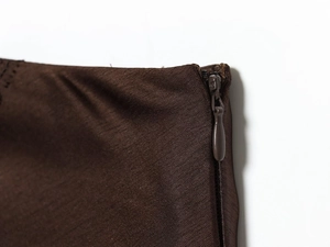 Détail de la fermeture éclair invisible sur jupe mi-longue en satin dentelle marron