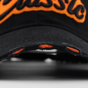 Detail of distressed black cotton baseball cap brim with orange contrast underlay