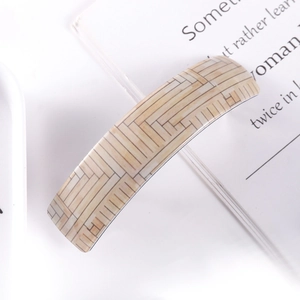 Detail of a beige hair clip with geometric wood grain pattern and a rectangle design