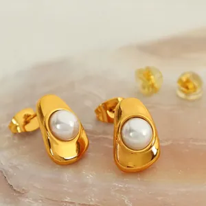 Elegant gold irregular oval earrings with pearl inlays on a soft pink stone surface