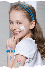 Close-up of glitter mermaid temporary tattoos and blue beaded bracelet on a girl's arm