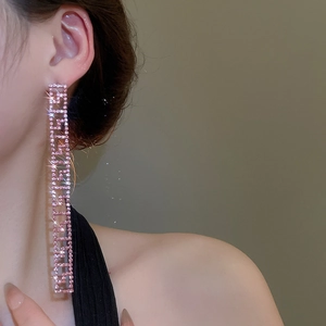 Dettaglio degli orecchini a nappine lunghe con strass rosa e design geometrico