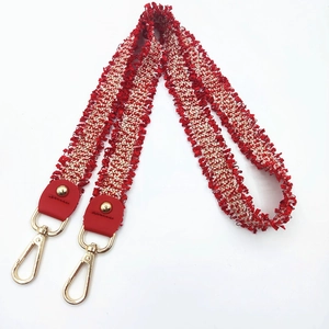 Red and white woven wide bag strap with bohemian fringe edges and golden metal lobster clasps