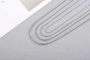 Detail showing four silver stainless steel snake chain necklaces in various lengths