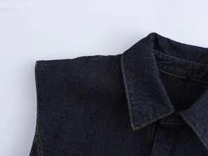 Détail du col et de l'épaule d'un gilet en jean foncé avec surpiqûres jaunes