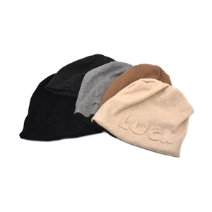 Detail of five-color knit beanies with embossed LUCK lettering and soft texture