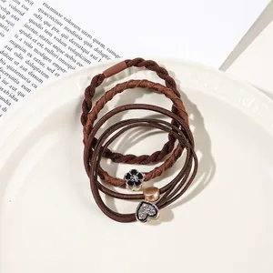 Close-up of brown elastic hair bands with heart and flower charms on a ceramic tray
