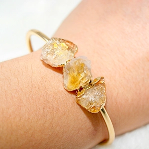 Detail of adjustable gold-plated bracelet with three raw yellow citrine gemstones
