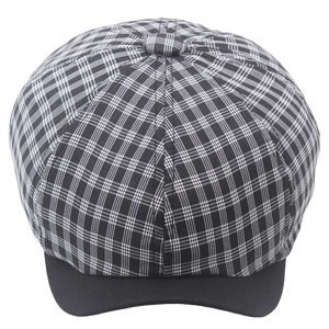 Detail of checkered newsboy cap showing black and white plaid pattern and black cotton brim
