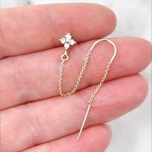 Macro shot of silver S925 tassel earrings with sparkling clover zircon pendants on fingertips