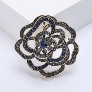 Detailed view of vintage bronze flower brooch with deep blue and grey crystal inlays