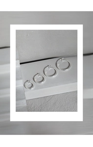 Macro view of four assorted sizes of polished S925 sterling silver hoop earrings on stone