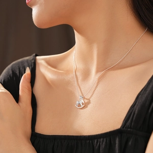 Gros plan d'un collier avec pendentif cheval à bascule en argent sur le cou