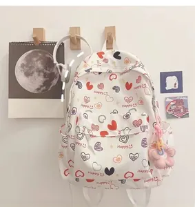 Detail view of white canvas backpack with colorful heart patterns and plush floral charm