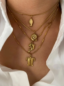 Close-up of golden ocean-themed layered necklaces with turtle, dolphin and shell pendants