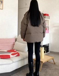 Detail view of the back of a brown casual puffer jacket for women in indoor setting