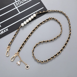 Detail of crossbody chain with black leather, gold metal, pearls and floral charms