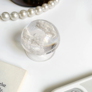 Close-up of a clear crystal ball phone grip with white feather filling on a clean surface