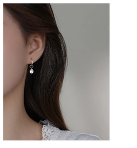 Close-up of S925 sterling silver drop earrings with clear zircon pendant on a model